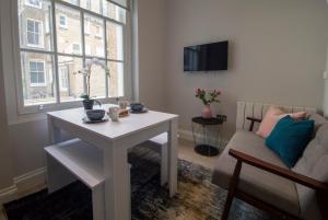 a living room with a table and a couch and a window at High Street Kensington by Viridian Apartments in London