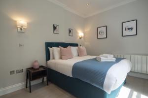 a bedroom with a large bed with pink and blue sheets at High Street Kensington by Viridian Apartments in London