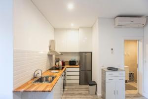 Una cocina blanca con fregadero y refrigerador. en Seaside 1BR Flat w/ AC in Matosinhos by LovelyStay, en Matosinhos