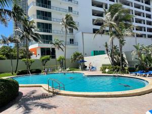 a large swimming pool with palm trees and a building at Ocean view Hollywood in Hollywood