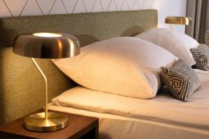 a bed with two pillows and a lamp on a table at Xerion Hotel in Kraków