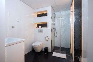 a white bathroom with a toilet and a shower at Xerion Hotel in Kraków