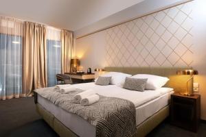 um quarto de hotel com uma cama grande com toalhas em Xerion Hotel em Cracóvia