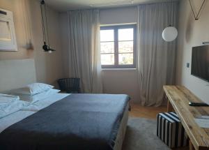 a bedroom with a bed and a desk and a window at DESIGN hotel VERBENICUM in Vrbnik