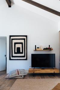 uma sala de estar com uma televisão de ecrã plano na parede em Monte da Fonte na Zambujeira do Mar