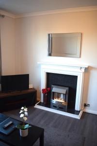a living room with a fireplace with a mirror above it at Kelpies Serviced Apartments - McClean in Falkirk