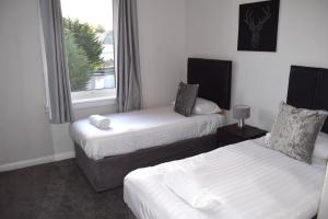 a hotel room with two beds and a window at Kelpies Serviced Apartments - McClean in Falkirk