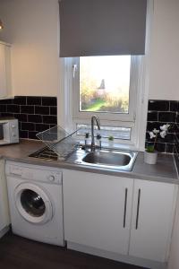 Il comprend une cuisine équipée d'un évier et d'un lave-linge. dans l'établissement Kelpies Serviced Apartments - McClean, à Falkirk