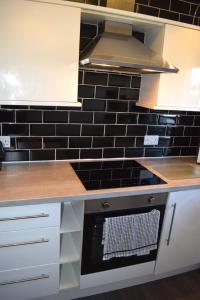 a kitchen with black tiles on the wall at Kelpies Serviced Apartments - McClean in Falkirk