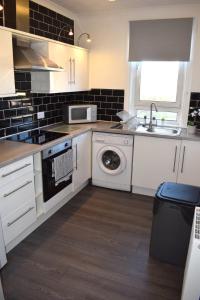 a kitchen with a sink and a washing machine at Kelpies Serviced Apartments - McClean in Falkirk