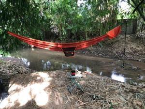 un hamac suspendu au-dessus d'une rivière dans une forêt dans l'établissement บ้านย่า ณ ท่าไทร, à Si Racha
