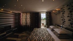 Schlafzimmer mit einem Bett, einem TV und einem Fenster in der Unterkunft Hotel EZIO in Chişinău