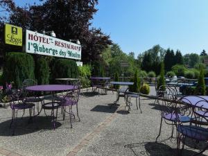 un groupe de tables et de chaises avec un signe dans l'établissement Auberge des Moulins, à Baume-les-Dames