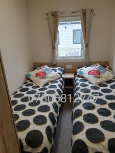 two beds in a small room with a window at J S RETREATS @ TATTERSHALL LAKES in Tattershall