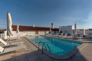 a swimming pool with chairs and umbrellas on a building at Monte Vale - Organic Farm in Entradas