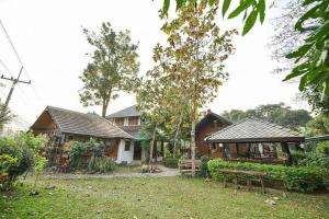 una casa con un banco delante de ella en จำค่า ชาเลท์ บ้านพักสวนเกษตร (Jumka Chalet - Home and Farm Stay), en Ban Cham Kha