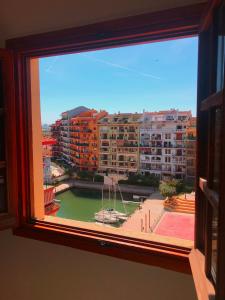 a window with a view of a city with buildings at Sea You Apartamentos Valencia Port Saplaya in Port Saplaya