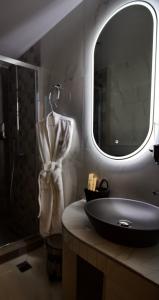 ein Bad mit einem Waschbecken, einem Spiegel und einer Dusche in der Unterkunft ODI ARTSPITALITY in Volos