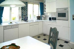 a kitchen with white cabinets and a table with a chair at Holiday Home Witsum - DNS10055-F in Hedehusum