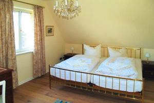 a bedroom with a bed with white sheets and a chandelier at Holiday Home Witsum - DNS10055-F in Hedehusum