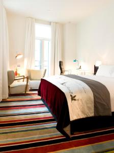 a bedroom with a bed and a chair and window at Hotel DeBrett in Auckland