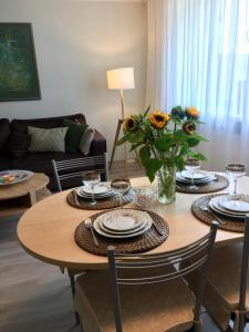 ein Wohnzimmer mit einem Tisch mit Platten und Blumen darauf in der Unterkunft Central Park Apartment Birštonas in Birštonas