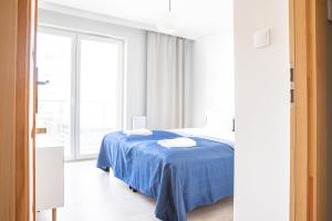 a bedroom with a bed with a blue blanket at AL-DOM apartamenty Apartament Stjarne in Kołobrzeg