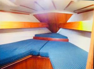 uma pequena cama na parte de trás de um barco em Cosy Sailing Boat Glamping Accommodation on the River in Sandwich em Sandwich