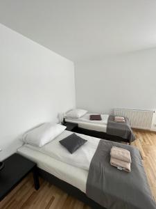 two beds in a room with white walls and wooden floors at Abra Apartament in Poznań