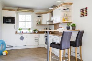 a kitchen with white cabinets and black bar stools at Holiday house, Fuhlendorf in Fuhlendorf