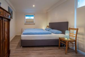 sypialnia z łóżkiem z niebieskimi poduszkami i krzesłem w obiekcie Das Blaue Haus w mieście Boppard