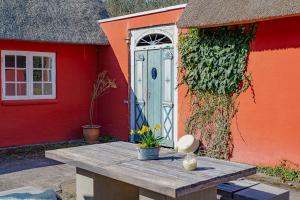 a table in front of a red building with a blue door at Poppelgaarden Rømø B&B in Rømø Kirkeby