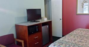 Habitación de hotel con TV en un tocador con cama en Budget Inn Fairport en Fairport