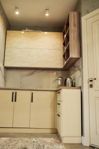 a kitchen with white cabinets and a wooden cabinet at Santorini in Chişinău