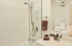 a white bathroom with a shower and a sink at Bavarian Motel in Invercargill