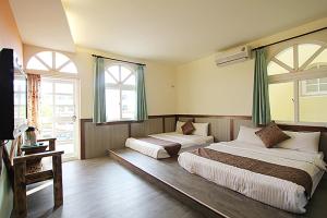 1 dormitorio con 2 camas y 2 ventanas en Da Wan Hostel, en Kenting