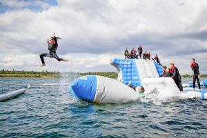 un grupo de personas saltando de una balsa inflable en Camp David Sport Resort holiday complex on Lake Schladitz, Rackwitz, en Rackwitz