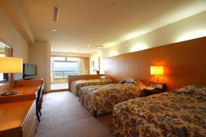 a hotel room with two beds and a television at Hotel Parens Onoya in Asakura