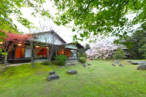 a house with a yard with rocks in front of it at Hotel Parens Onoya in Asakura