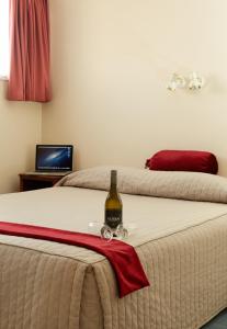 a bottle of wine sitting on top of a bed at Bavarian Motel in Invercargill
