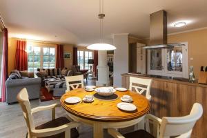 Il dispose d'une cuisine et d'un salon avec une table et des chaises en bois. dans l'établissement Holiday house, Fuhlendorf, à Fuhlendorf