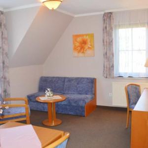 a living room with a blue couch and a table at Apartmenthaus Spreewaldperle in Burg