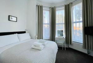 una camera da letto con un letto bianco con due asciugamani di The Gateway Hotel a Londra