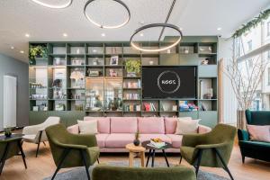 a living room with a pink couch and a tv at KOOS Hotel&Apartments - City Aparthotel in Munich +104 photos