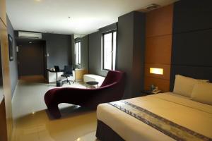 1 dormitorio con cama, silla y escritorio en B Fashion Hotel, en Yakarta