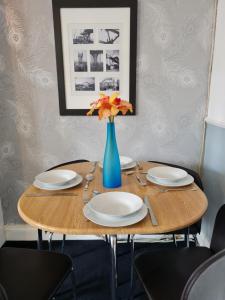 une table avec des assiettes et un vase avec des fleurs. dans l'établissement Entire Premium Holiday Cottage, à Monkwearmouth