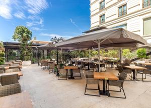 an outdoor patio with tables and chairs and umbrellas at Wyndham Grand Istanbul Kalamış Marina Hotel in Istanbul
