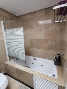 a bathroom with a bath tub and a toilet at Penthouse 6-8 personnes in Manilva +17 photos