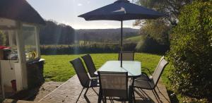 a table and chairs with an umbrella on a patio at Quintessential, secluded South Devon cottage in Plymouth