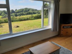 a living room with two windows with a view of a field at Quintessential, secluded South Devon cottage in Plymouth